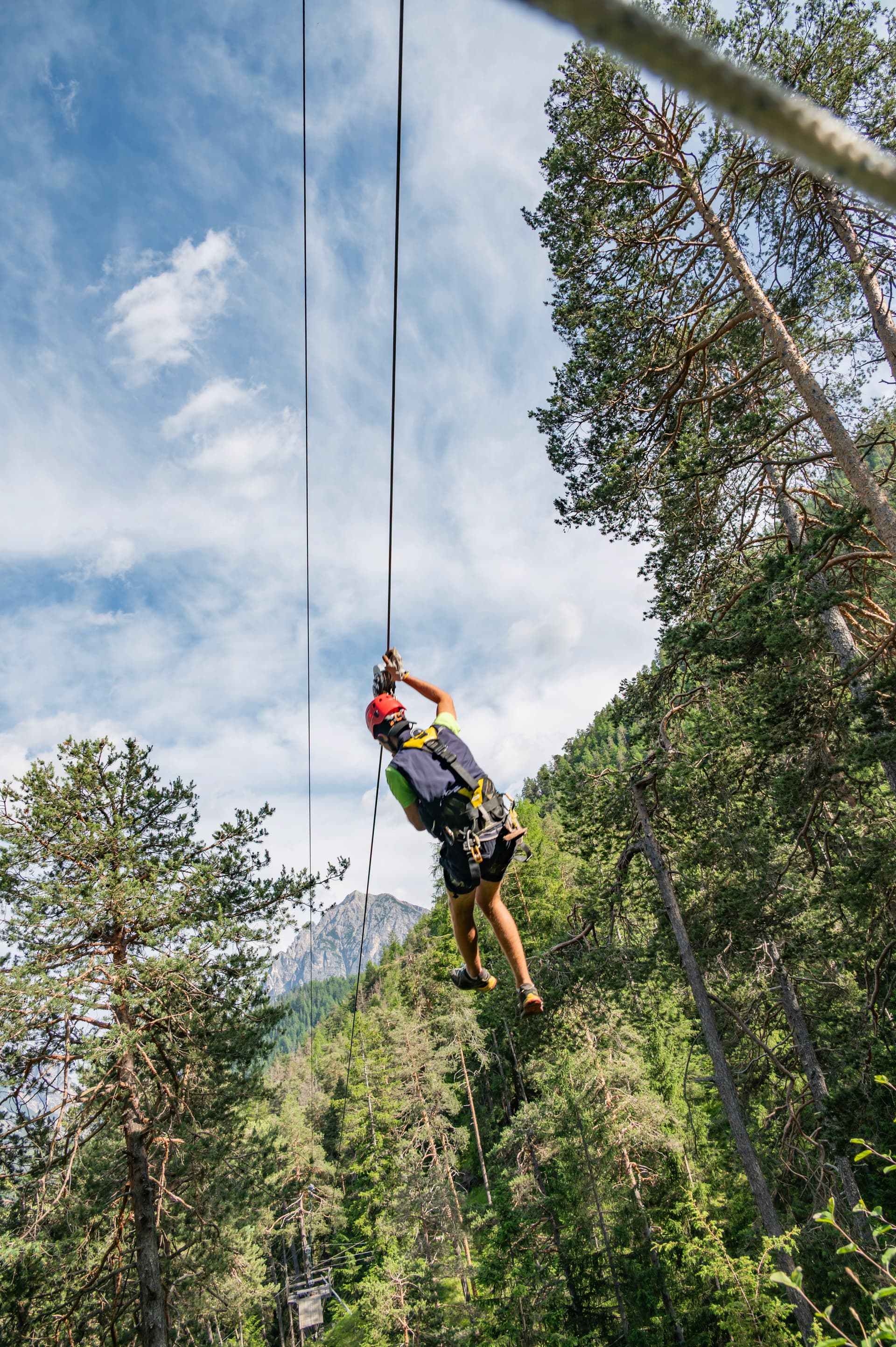 Flying on the zipline through trees with mountain views