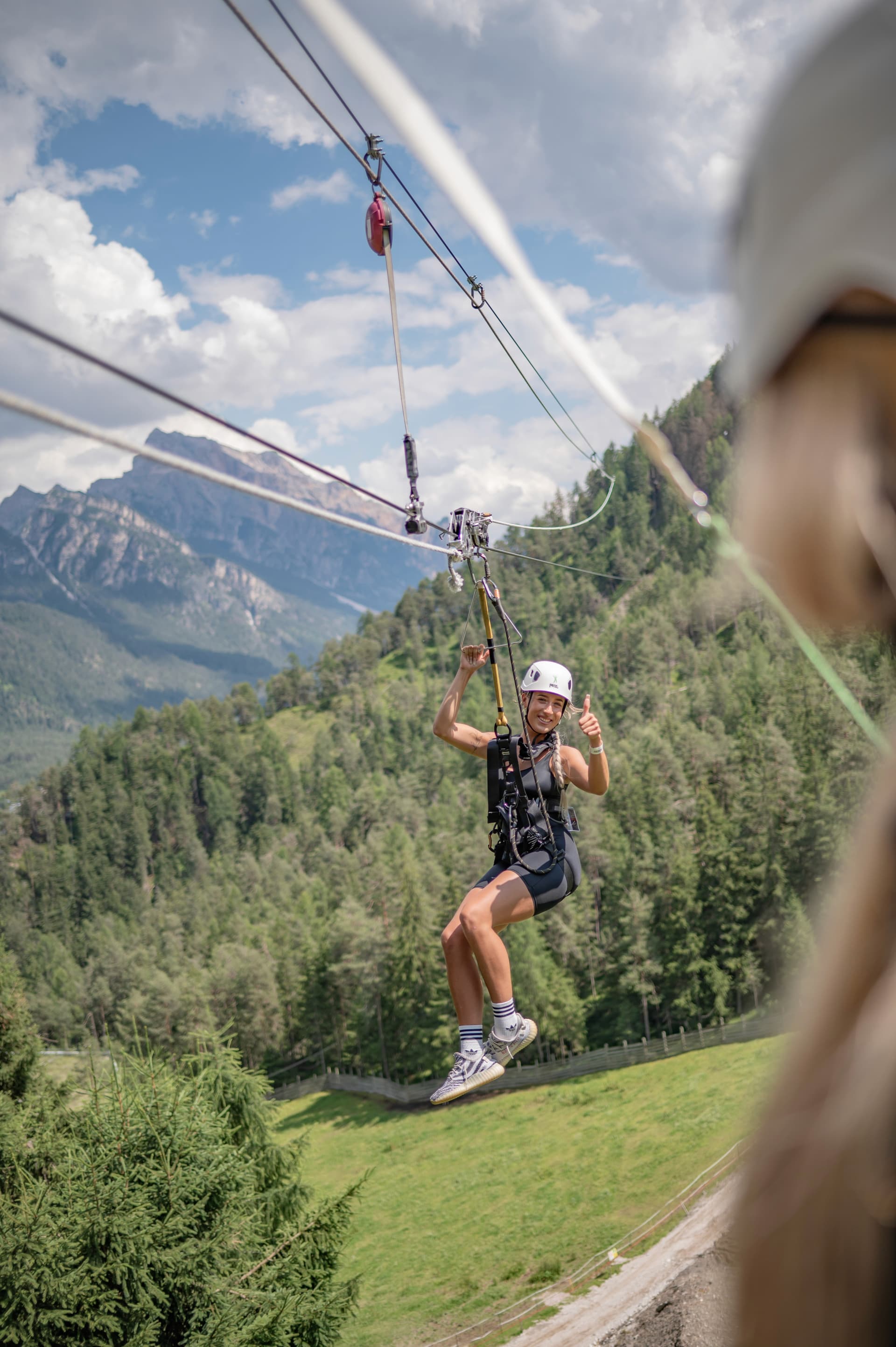 Smiling arrival on zipline with mountains behind